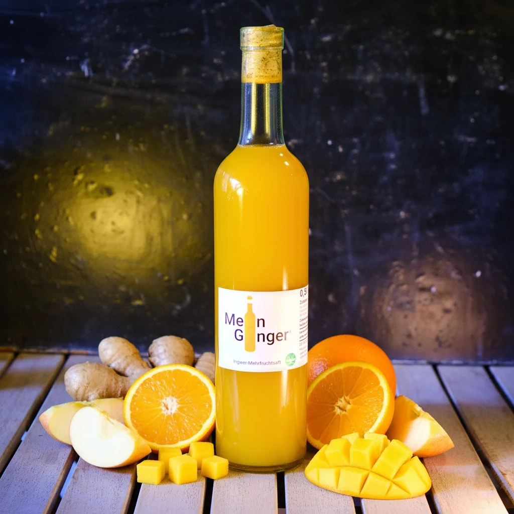 Eine Flasche Mein Ginger Original mit Ingwer, Äpfeln, Orangen und Mango nebendran